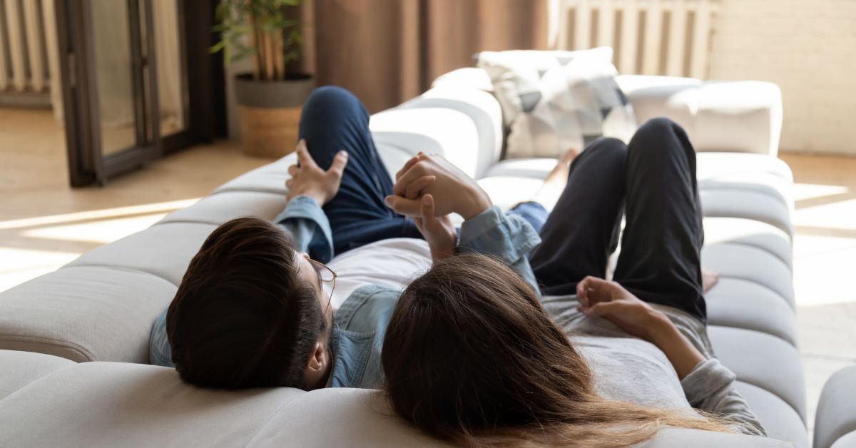 two people lying on a sofa holding hands